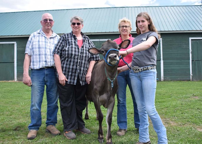 Lot 23 - Meadow Winds I Venus sold for $5600. Consigning this stylish Sr. Calf was Roger & Elizabeth Czadzeck, Clyde, NY. (pictured on the left of the heifer) Sara Barlass, AJCA Area Rep (back) represents the buyers, Sam, Angela, George Colpetzer, Greenville PA, Grace Stroud is on the halter